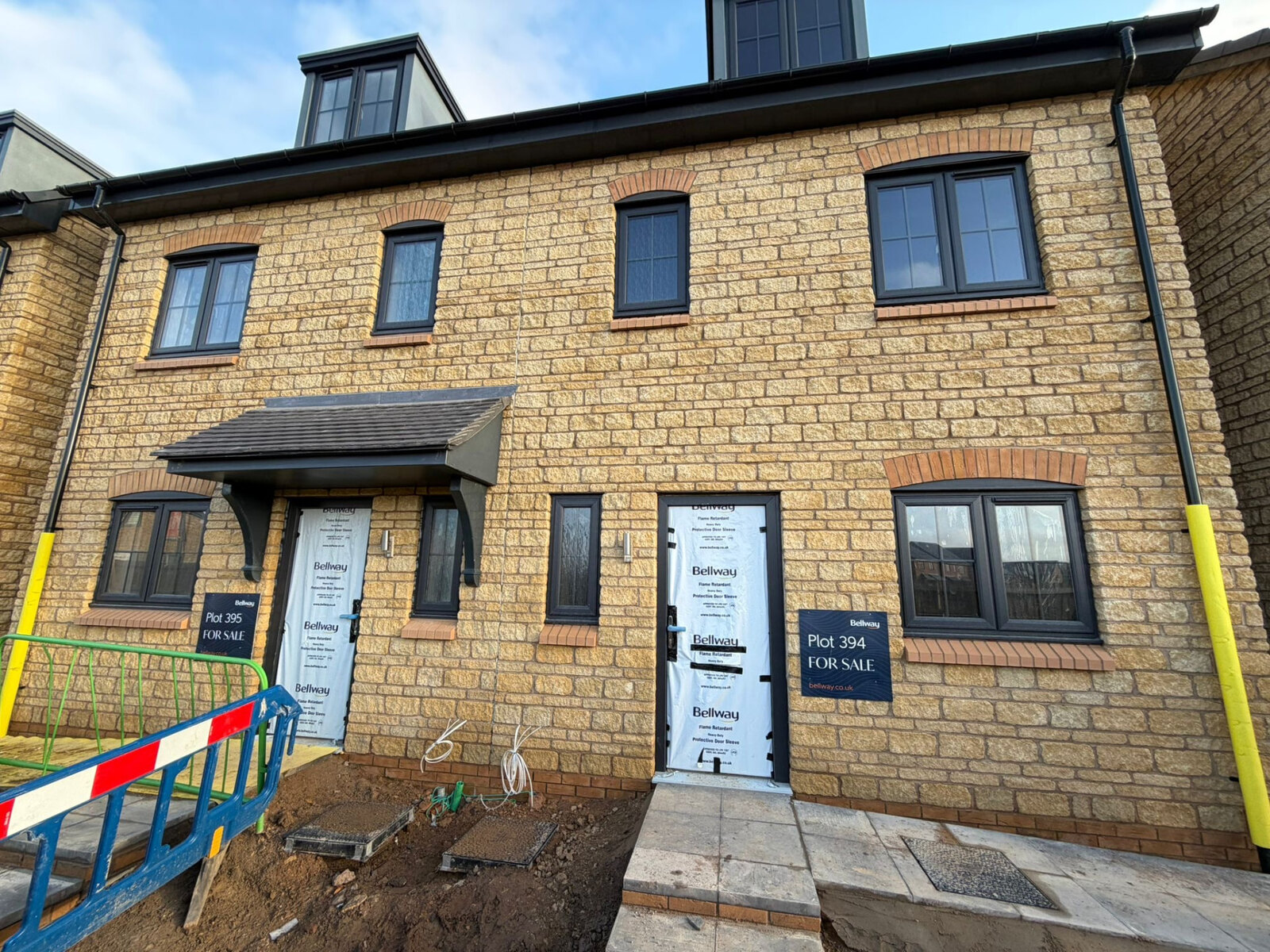 Terrace of new build homes in reconstituted stone with brick arch heads and cills