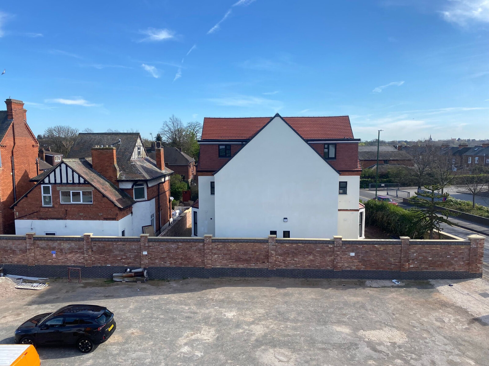 Completed long brick boundary wall with piers, blue brick plinth and coping in Nottingham
