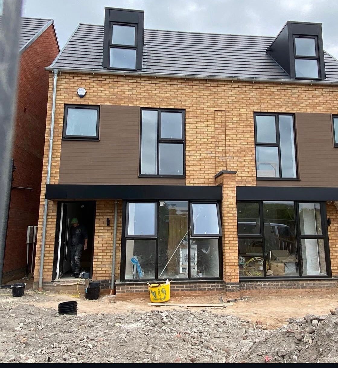 Modern pair of new build homes with buff brick elevations, dormer windows and large glazed openings