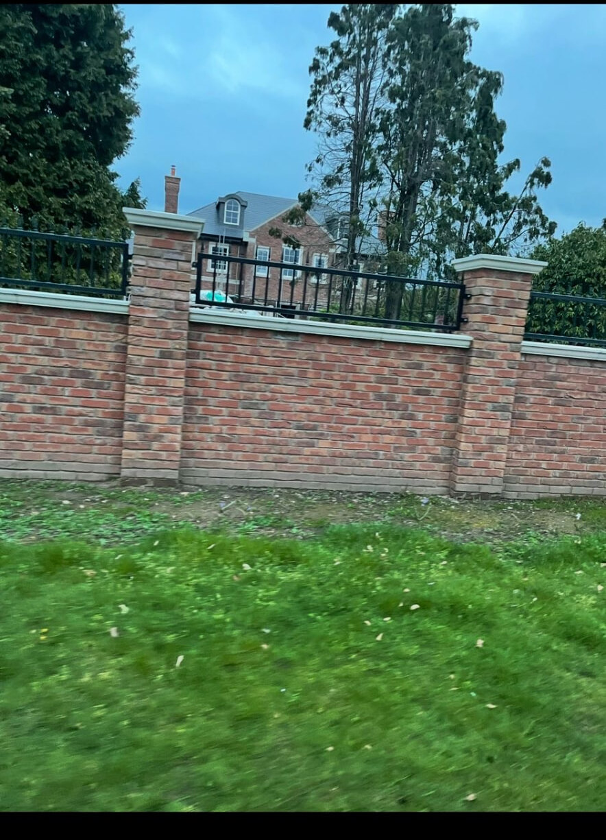 Brick boundary wall with stone copings and black railings in Bramcote
