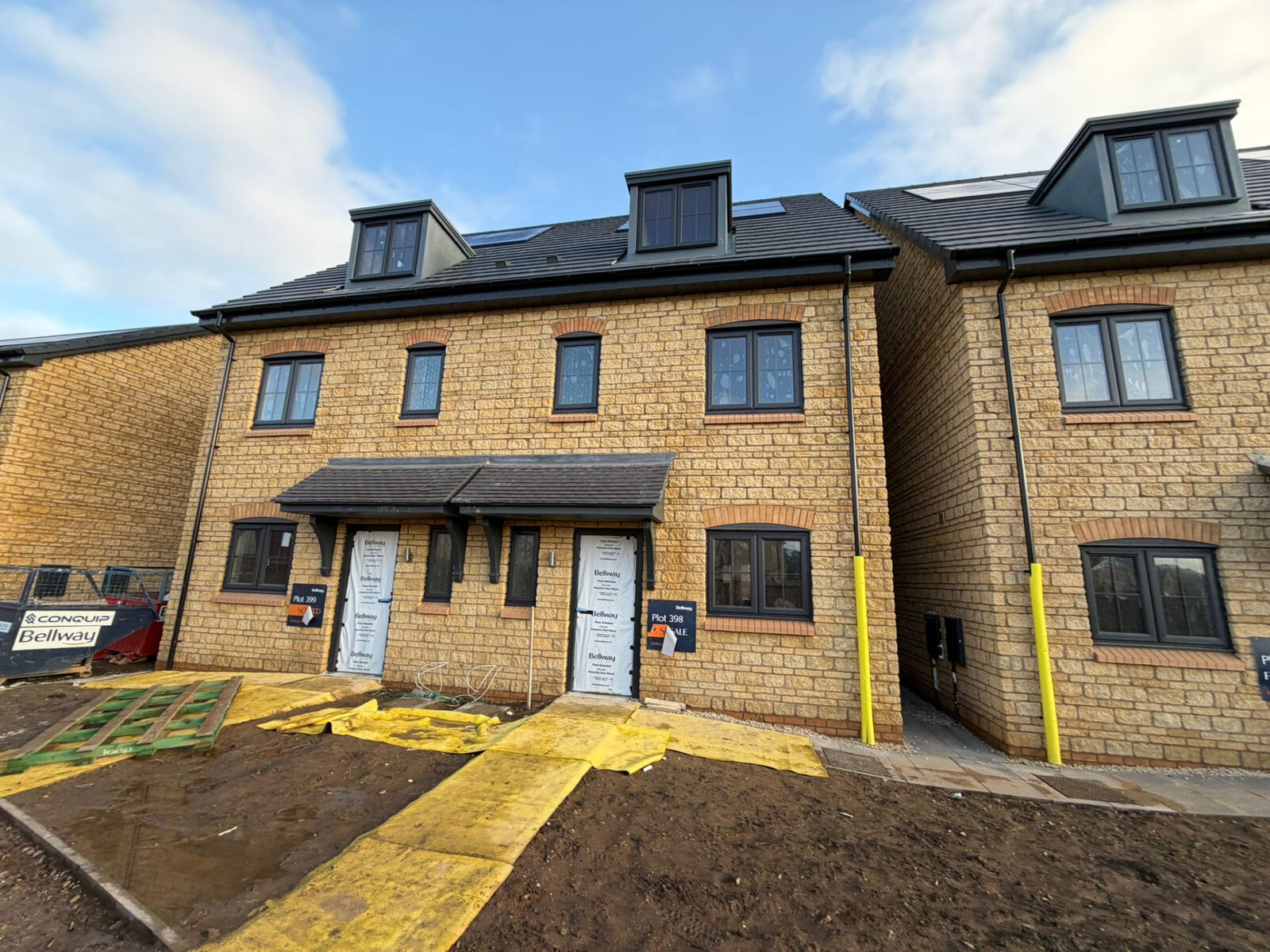 Three storey new build townhouses in reconstituted stone with red brick window arches