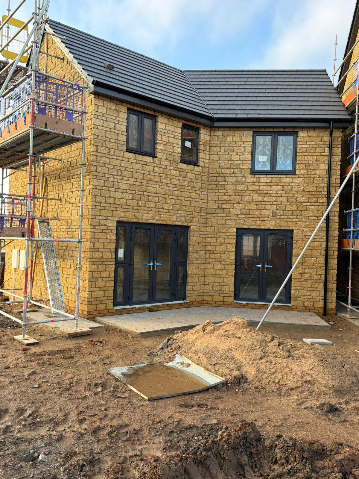 New build stone house under construction with scaffolding in place around the elevations