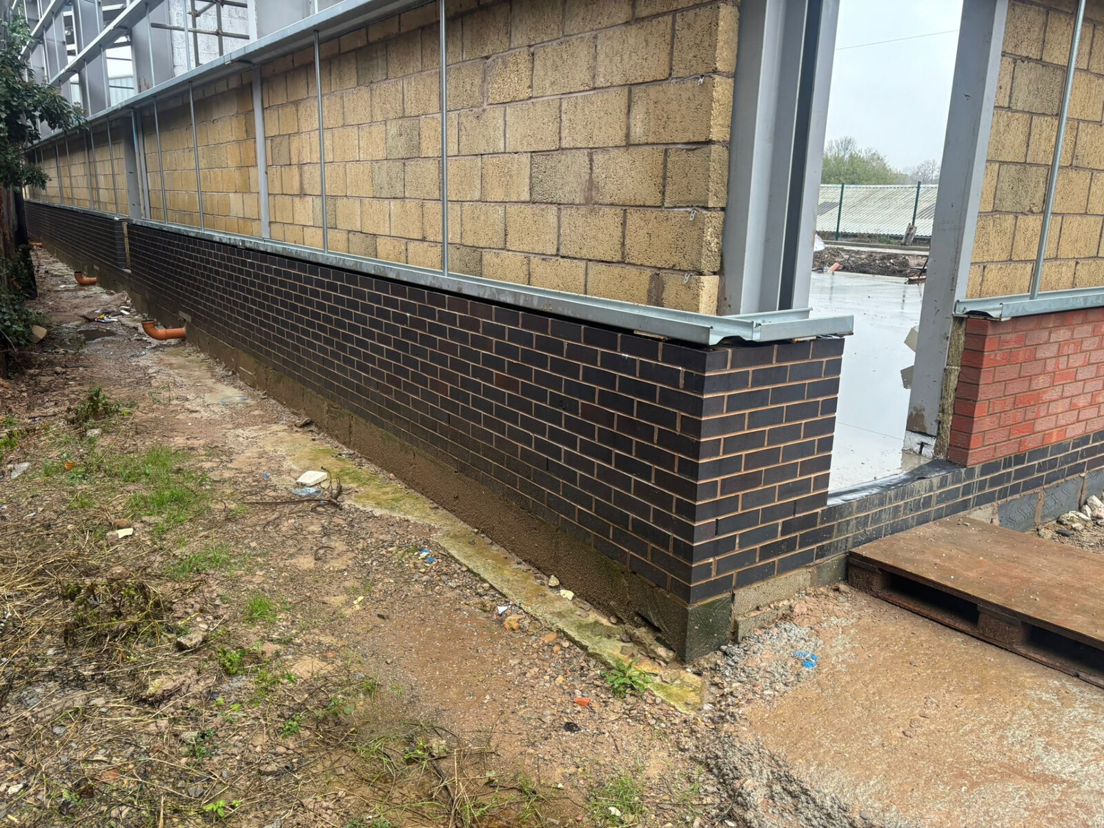 Long blue brick plinth wall and blockwork to a commercial unit under construction