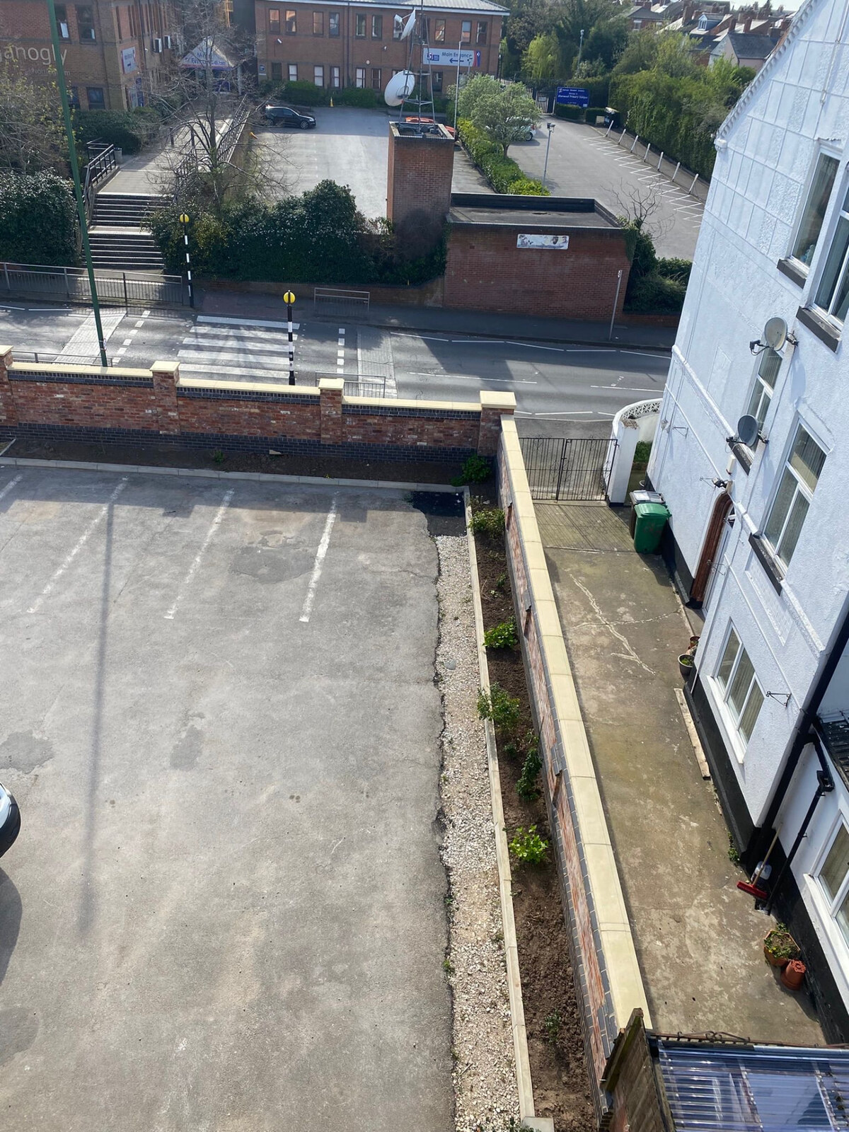 Brick retaining and planter wall with stone coping alongside a car park