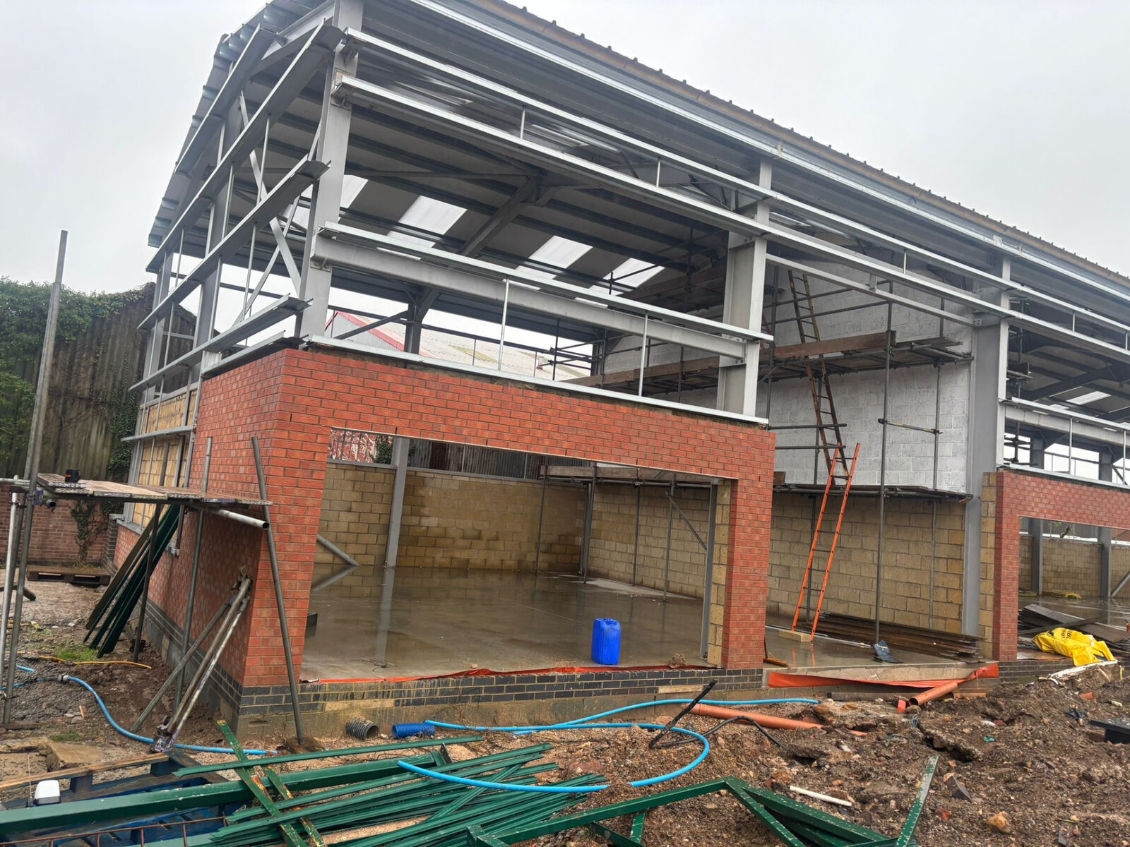 Commercial unit under construction with brick piers, blockwork panels and a steel portal frame