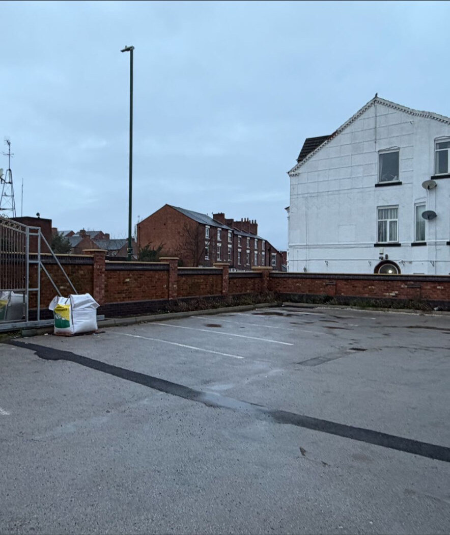Brick car park boundary wall with piers and gated entrance